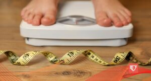 osoba stojąca na wadze, obok leży miarka